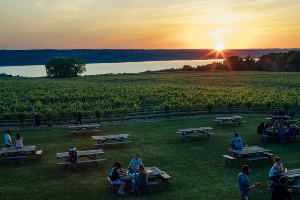Picnic tables at sunset with people drinking and eating