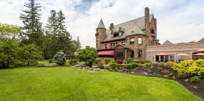 The lawn at Belhurst Castle winery that features a brick castle building with outdoor seating