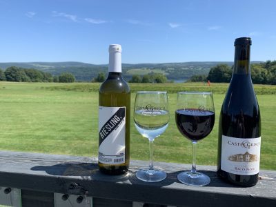 Glasses of white and red wine from Castel Grisch winery overlooking the vineyard and lake