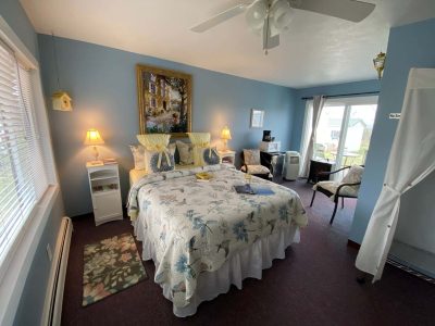 Blue bedroom with bed, chair, cozy lamps, and sliding glass doors at the Savannah House