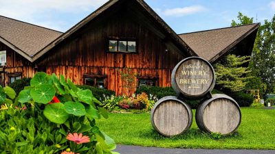 Entrance sign to Wagner Vineyards estate winery that features old wine barrels with an arrown sign