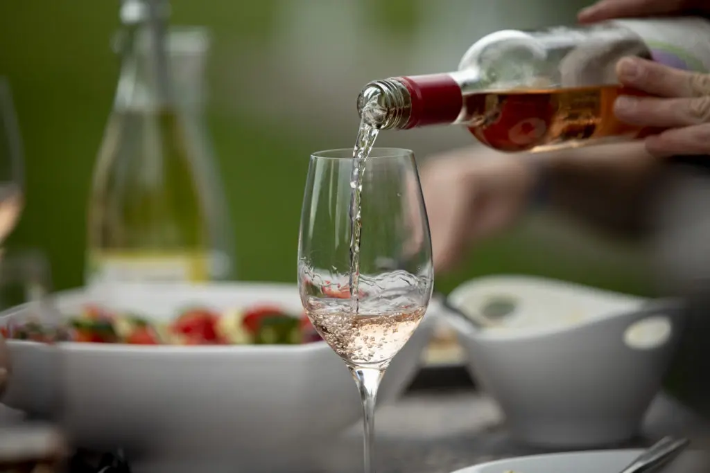 Glass of rose with wine pouring into it